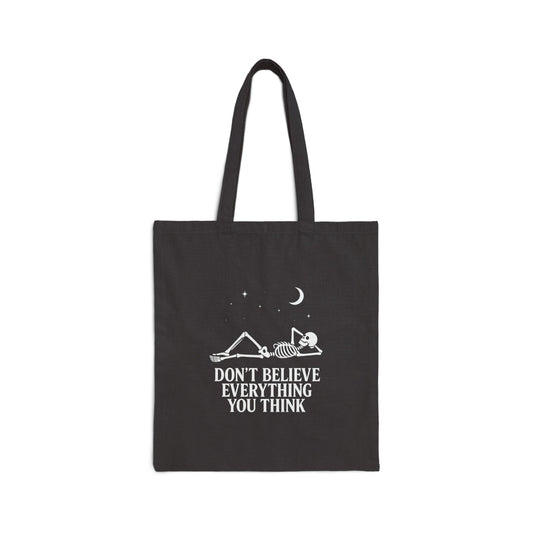Minimalist skeleton silhouette tote bag with gothic quote “Don’t believe everything you think” under crescent moon and stars – SkeletonWear Apparel