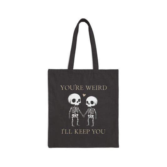Two skeletons holding hands with a red heart, quirky “You’re Weird I’ll Keep You” text, gothic skeleton couple tote bag by SkeletonWear Apparel