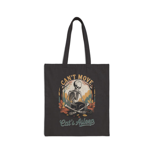Relaxed skeleton cradling black cat with eyes closed – cozy gothic fall tote bag by SkeletonWear Apparel