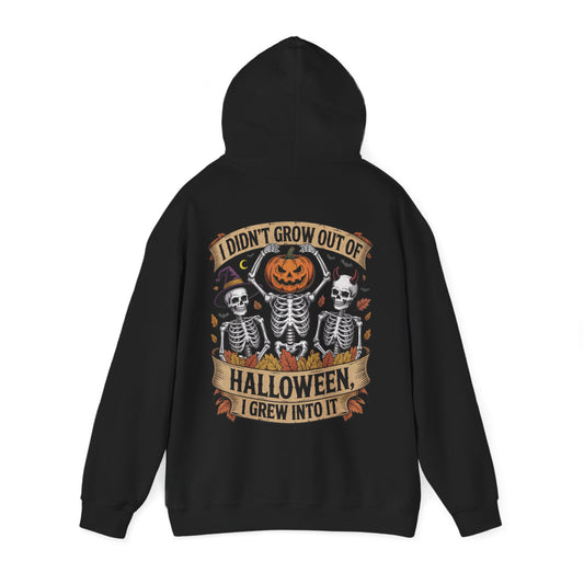 Skeletons with pumpkin, witch hat, and devil horns under banner ‘I Didn’t Grow Out of Halloween, I Grew Into It’ – SkeletonWear Apparel Halloween hoodie design