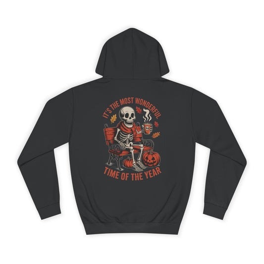Skeleton wearing scarf drinking pumpkin spice latte on gothic bench with pumpkins and autumn leaves – cozy Halloween hoodie design by SkeletonWear Apparel